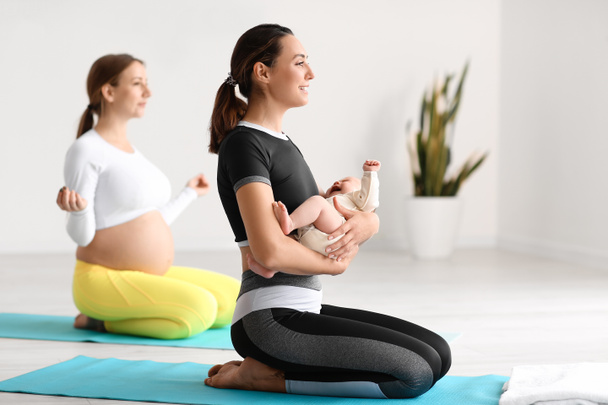 Giovane donna incinta che fa yoga con allenatore e piccolo bambino in palestra - Foto, immagini