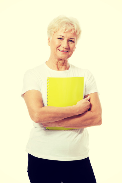 An old woman holding a workbook. - Фото, зображення