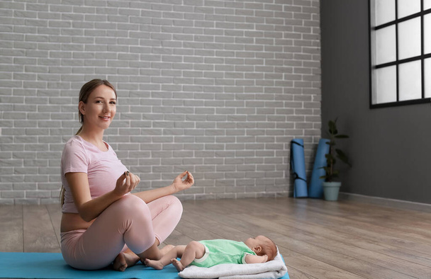 Jovem grávida com pequeno bebê meditando no ginásio - Foto, Imagem