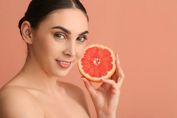 Красивая женщина с вырезанным грейпфрутом на цветном фоне - Фото, изображение