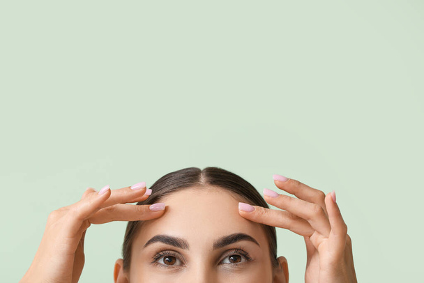 fiatal nő egészséges bőr megható homlok a színes háttér - Fotó, kép