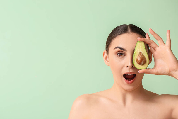 Surprised woman with fresh avocado on color background - Photo, Image