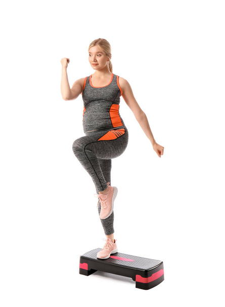 Young pregnant woman with aerobic stepper on white background - Foto, imagen
