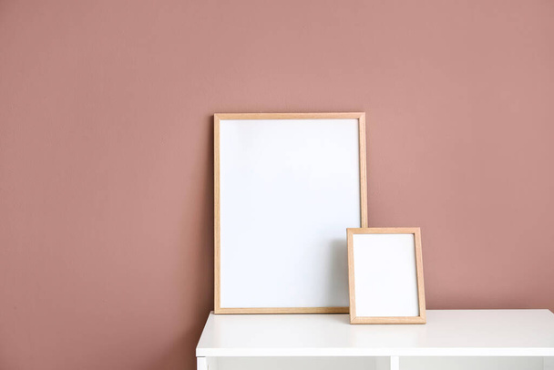 Blanco frames op witte plank in de buurt van kleur muur - Foto, afbeelding
