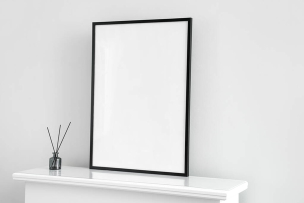 Blanco frame met rietstrooier op schoorsteenmantel bij lichte wand - Foto, afbeelding