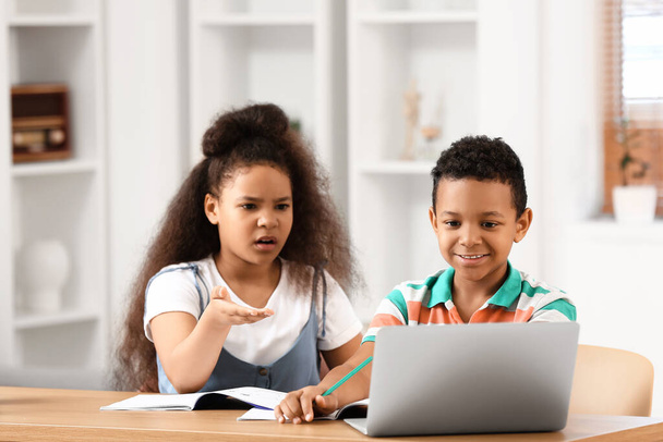 Little schoolchildren studying online at home - Фото, изображение