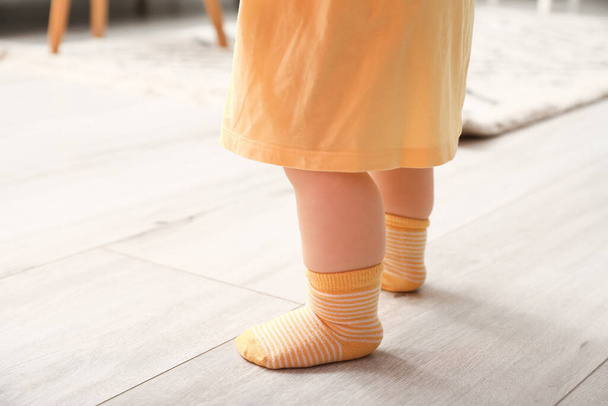 Nohy malé holčičky ve žlutých ponožkách se učí chodit doma, detailní záběr - Fotografie, Obrázek