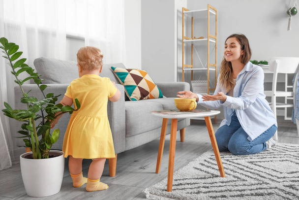 Carino neonata in abito giallo imparare a camminare con la madre vicino divano a casa - Foto, immagini