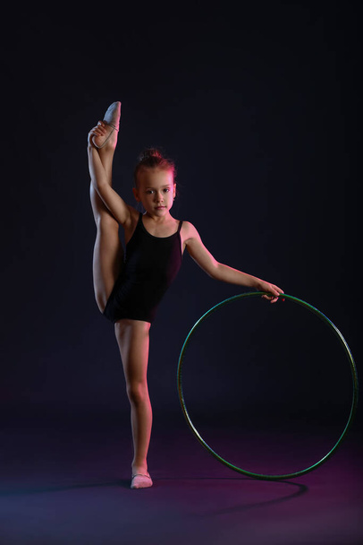 Little girl doing gymnastics  with hula hoop on dark background - 写真・画像