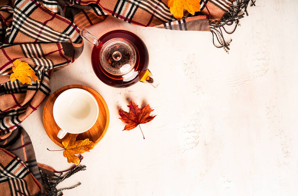 Autumn composition. A cup of tea and teapot, scarf, autumn leaves. Flat lay, top view, copy space - Fotó, kép
