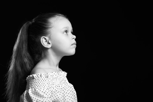 Black and white portrait of pretty little girl on dark background - Photo, Image