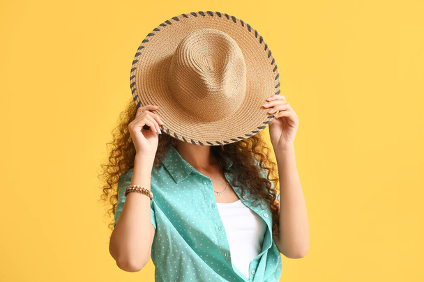 Mooie Afro-Amerikaanse vrouw met stijlvolle hoed op kleur achtergrond - Foto, afbeelding