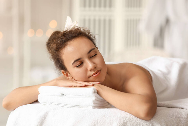 Młoda Afroamerykanka relaksująca się na kanapie w salonie spa - Zdjęcie, obraz