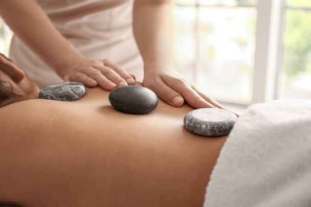 Young African-American woman getting massage with stones by therapist in spa salon, closeup - Foto, immagini