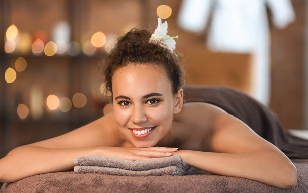 Belle femme afro-américaine couchée sur le canapé dans un salon de spa - Photo, image
