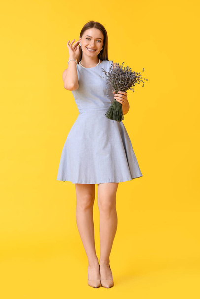 Mooie jonge vrouw met boeket van lavendel op kleur achtergrond - Foto, afbeelding