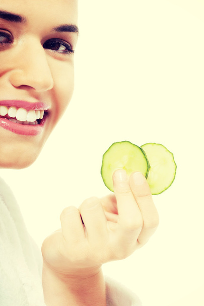 Beautiful woman in bathrobe holding slices of cucumber. - Foto, imagen