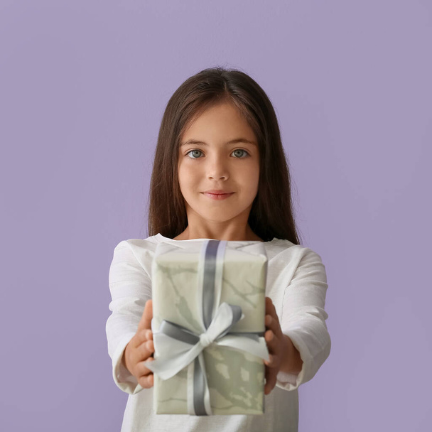 Little girl with gift on color background - Photo, Image