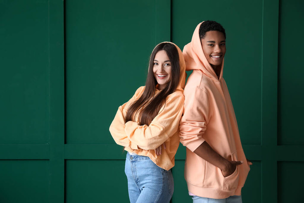 Stijlvol jong paar in hoodies op groene achtergrond - Foto, afbeelding
