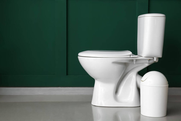 Toilet bowl with bin near green wall - Photo, Image