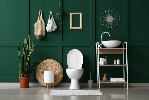 Εσωτερικό της τουαλέτας με λεκάνη, νεροχύτη και πράσινο τοίχο - Φωτογραφία, εικόνα