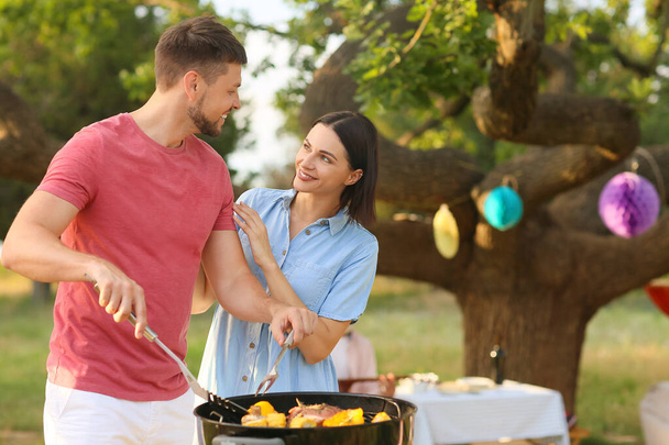 Happy couple cooking food at barbecue party on summer day - Photo, Image