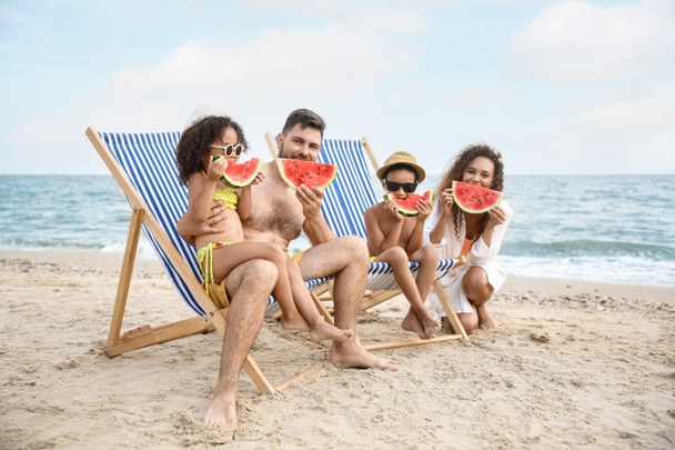 Familia feliz comiendo sandía en la playa del mar - Foto, Imagen