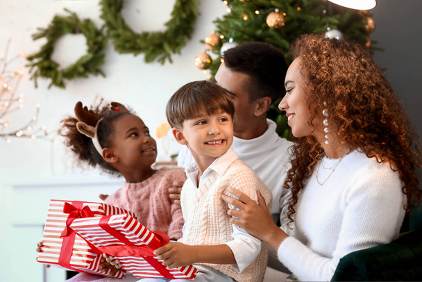 Ouders geven cadeautjes aan hun kinderen thuis op kerstavond - Foto, afbeelding