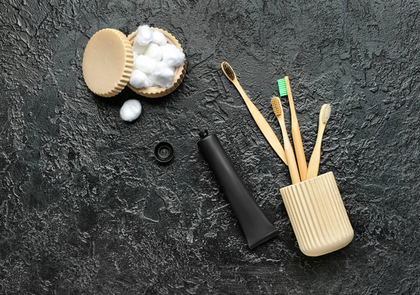 Aktif karbon diş macunu ile açılan tüp, bambu diş fırçası ve koyu arkaplanda pamuk topları olan tutucu. - Fotoğraf, Görsel