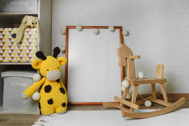 Mockup of the picture in the children's room. wooden horse and knitted toys. The interior of the nursery in beige colors. - Photo, Image