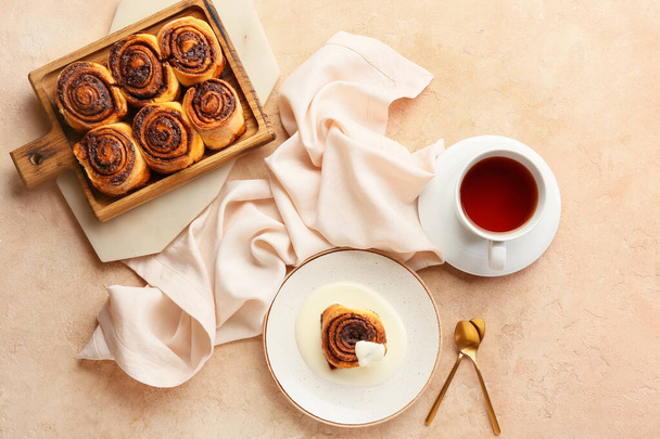 Wooden board and plate with tasty cinnamon rolls on beige background - Photo, Image