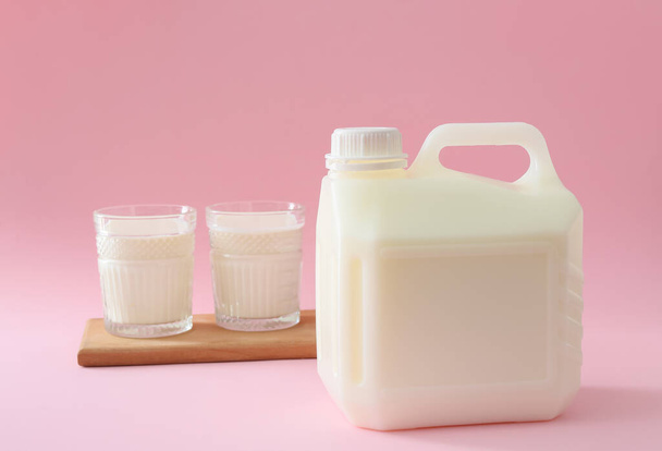 Gallon palack és pohár tej rózsaszín alapon - Fotó, kép