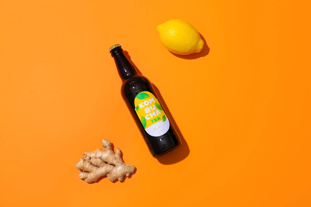Fles van natuurlijke kombucha met citroen en gember op kleur achtergrond - Foto, afbeelding