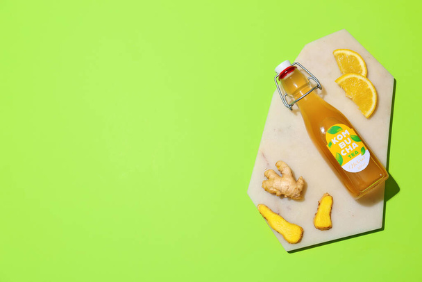 Bottle of tasty kombucha with ginger and lemon on color background - Foto, afbeelding