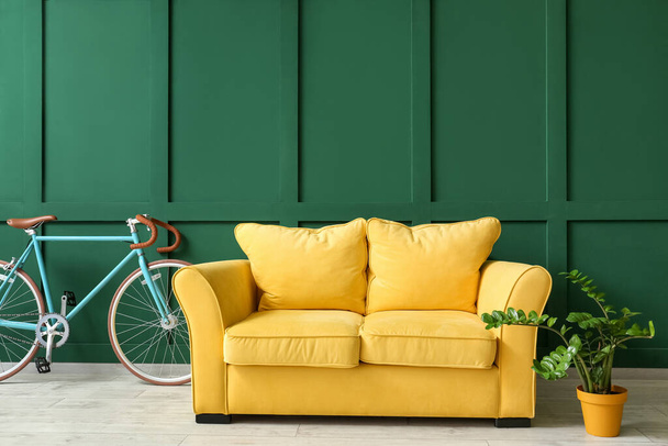 Divano giallo, bicicletta e piante d'appartamento vicino al muro verde - Foto, immagini