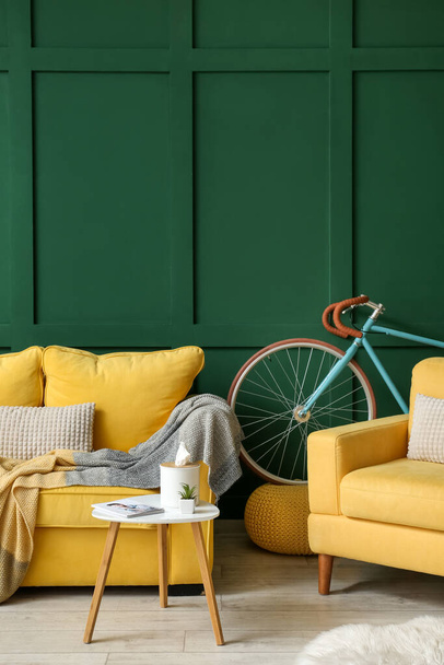 Interior del salón con sofá amarillo, sillón y bicicleta - Foto, imagen