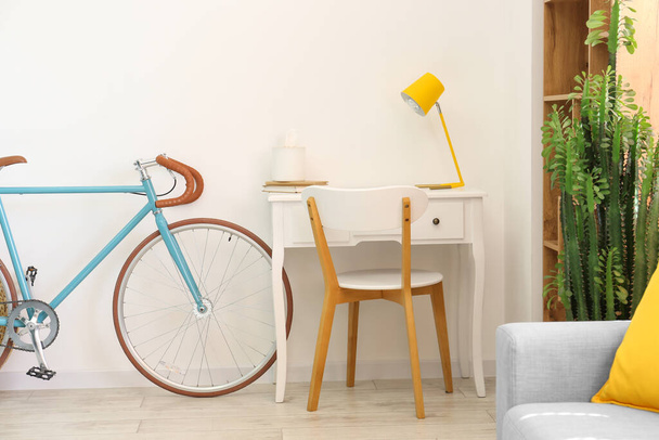 Modern workplace and bicycle near light wall - Photo, Image