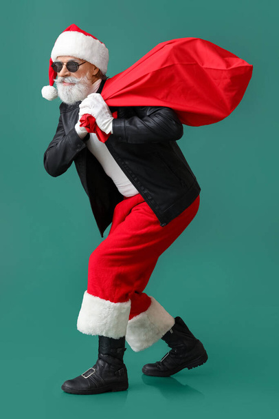 Cool Kerstman in lederen jas en met tas op kleur achtergrond - Foto, afbeelding