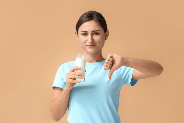 Junge Frau weigert sich, Milch auf farbigem Hintergrund zu trinken - Foto, Bild
