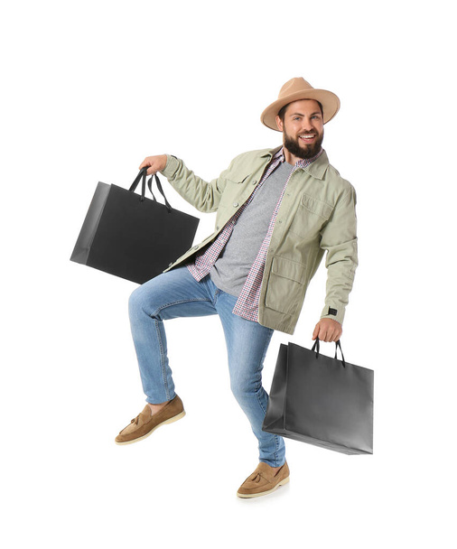 Handsome man with Black Friday shopping bags jumping on white background - Foto, afbeelding