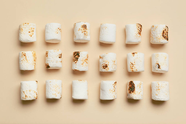 Tasty grilled marshmallows on beige background - Foto, afbeelding