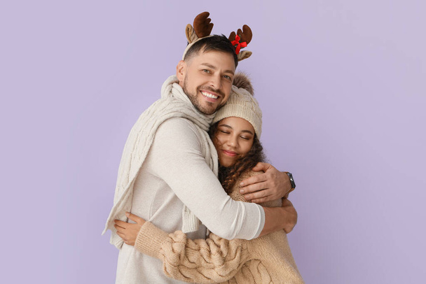 Happy hugging couple in winter clothes on color background - Foto, imagen