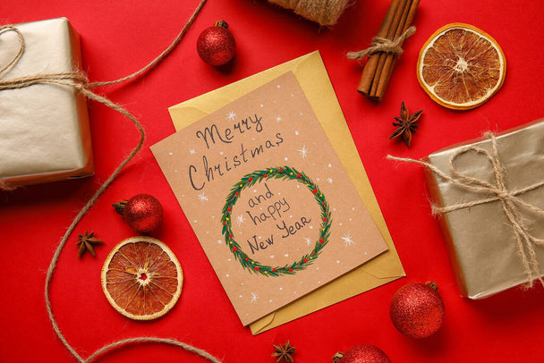 Presentes, cartão de saudação com texto MERRY CHRISTMAS E HAPPY NOVO ANO em fundo vermelho - Foto, Imagem