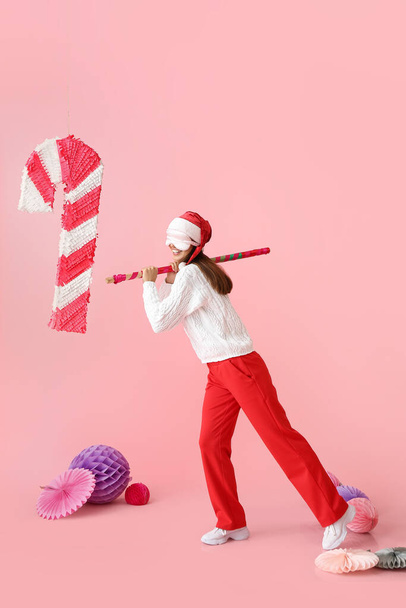 Krásná žena v klobouku Santa a s cukrovou třtinou pinata na barevném pozadí - Fotografie, Obrázek