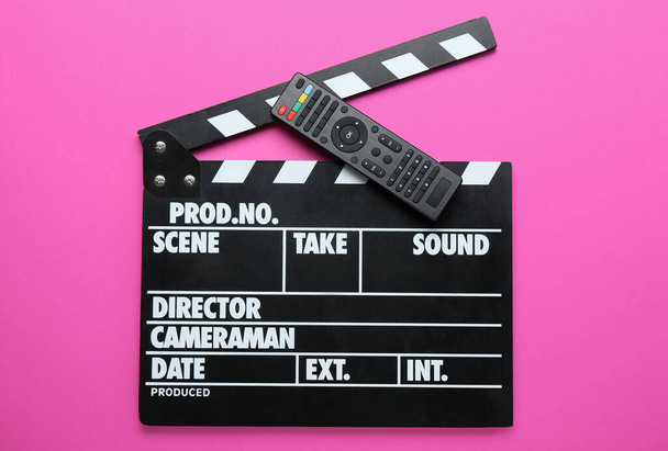 Modern TV remote control and clapperboard on pink background - Photo, Image