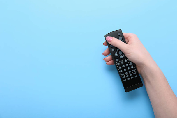 Female hand with TV remote controller on color background - Photo, Image