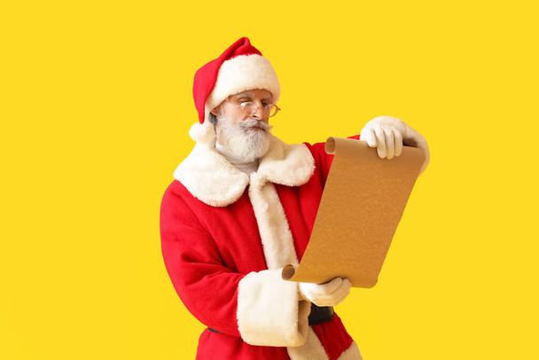 Papai Noel leitura lista de desejos no fundo amarelo - Foto, Imagem