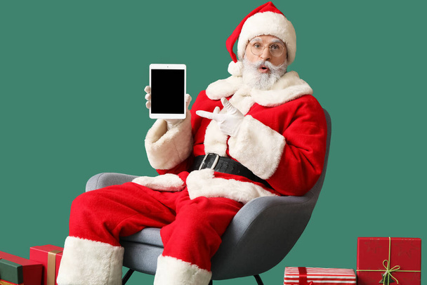 Yllättynyt Santa Claus tabletti tietokone värillinen tausta - Valokuva, kuva