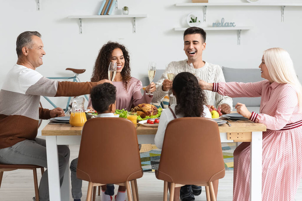 Happy family raising glasses at served table and celebrating Thanksgiving Day - Photo, Image