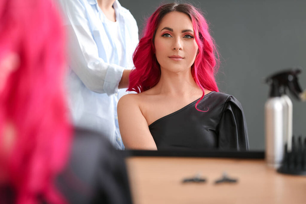 Stylistin frisiert junge Frau im Schönheitssalon - Foto, Bild